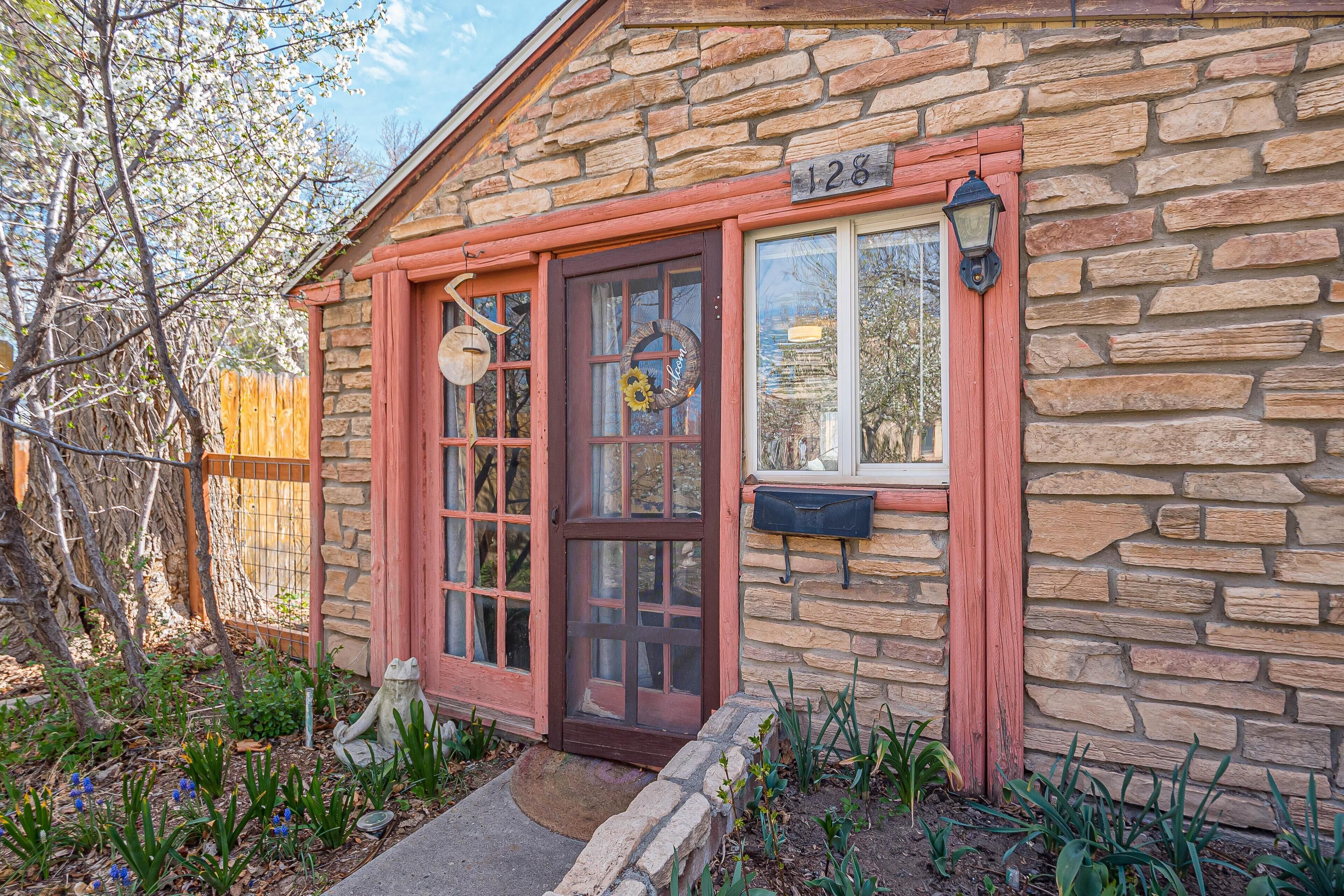 A stone house with a red door, numbered 128, and a mailbox.