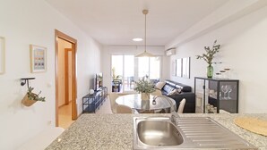 Uma cozinha moderna com bancadas de granito, uma pia de aço inoxidável e um espaço de jantar com mesa e cadeiras de vidro.