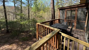 Eine Holzterrasse mit Tisch und Stühlen mit Blick auf ein bewaldetes Gebiet.