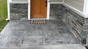 A wooden front door with a small window above it, set in a house with grey siding and stone accents around the entrance. - NEWLY BUILT condo - premium features, game room, firepit, short walk to village (Ellicottville)