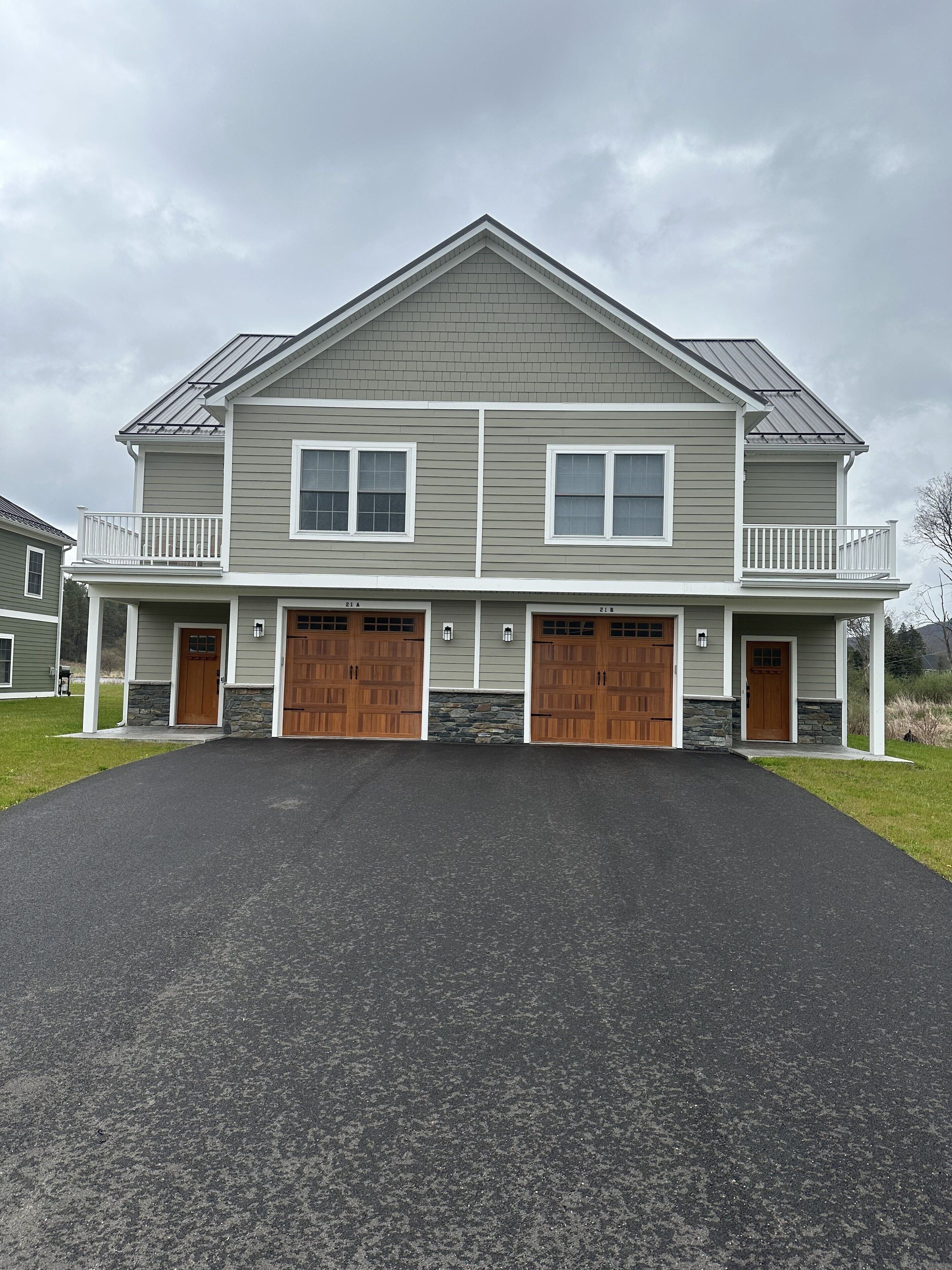 A two-story house with a front porch, two garages, and a stone foundation.