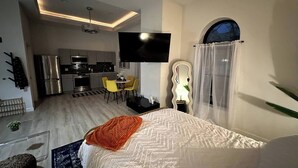 Een moderne hotelkamer met een bed, een televisie, een keukenhoek en een eethoek.