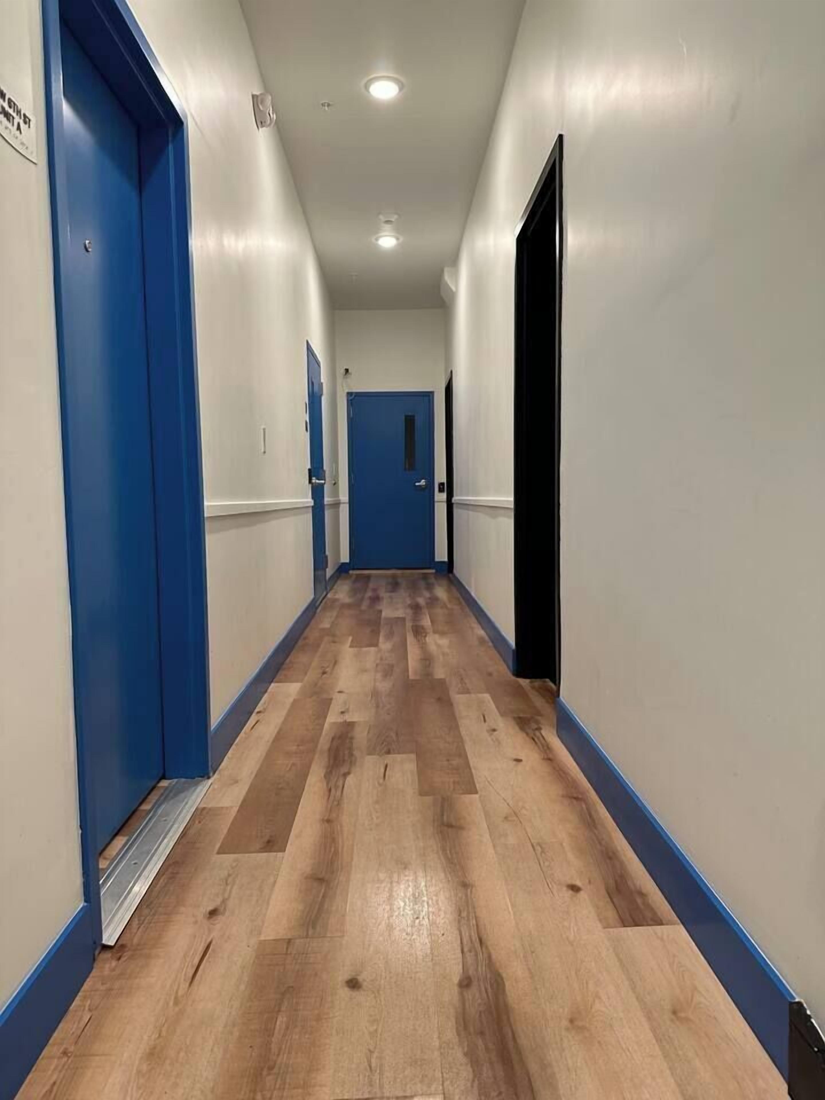 Un pasillo con puertas azules y suelo de madera.