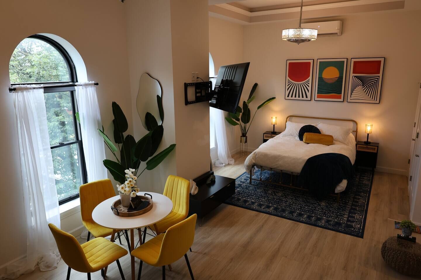 Een slaapkamer met een bed, nachtkastjes, een televisie en kunst aan de muur.