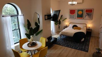 Een slaapkamer met een bed, nachtkastjes, een televisie en kunst aan de muur.