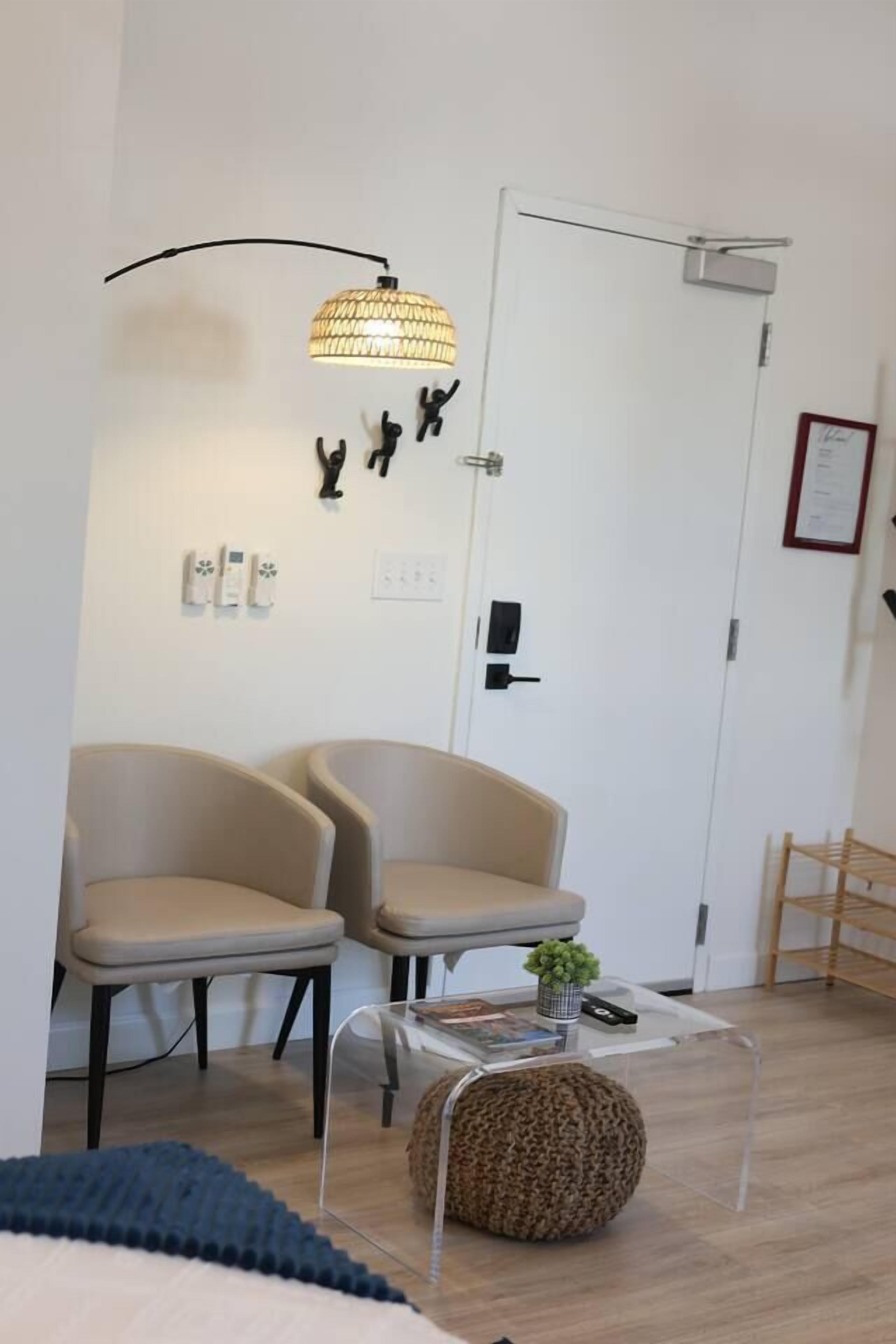A room with two chairs, a lamp, a door, and a small table with a plant.