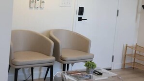 Een kamer met twee stoelen, een lamp, een deur en een kleine tafel met een plant.