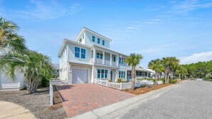 A two-story house with a garage, a driveway, and a white picket fence.