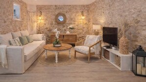 A living room with a sofa, armchair, coffee table, TV, and decorative items.