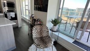 Una cocina moderna con horno empotrado y zona de comedor con una silla de estampado de leopardo y vistas a la ciudad.