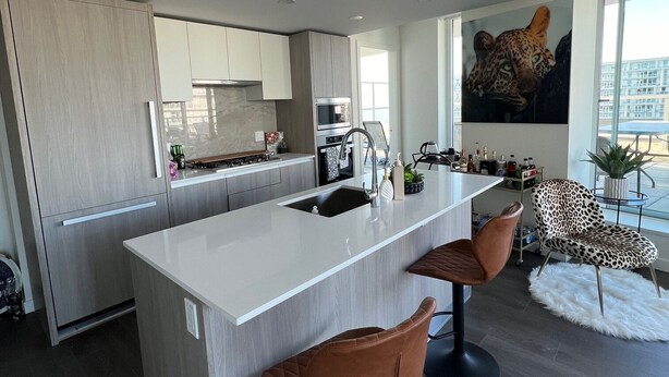 Una cocina moderna con una isla central, taburetes de bar y una silla estampada de leopardo.