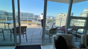 Una habitación moderna con ventanas amplias, un balcón y vistas a un paisaje urbano.