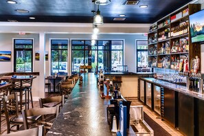 A bar area with a long counter, stools, and a variety of bottles and glasses. - Final Flag Villa 1b/1b (Carrabelle)