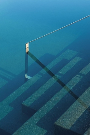 Une vue sous-marine d’une piscine avec une eau d’un bleu limpide et un plongeoir.