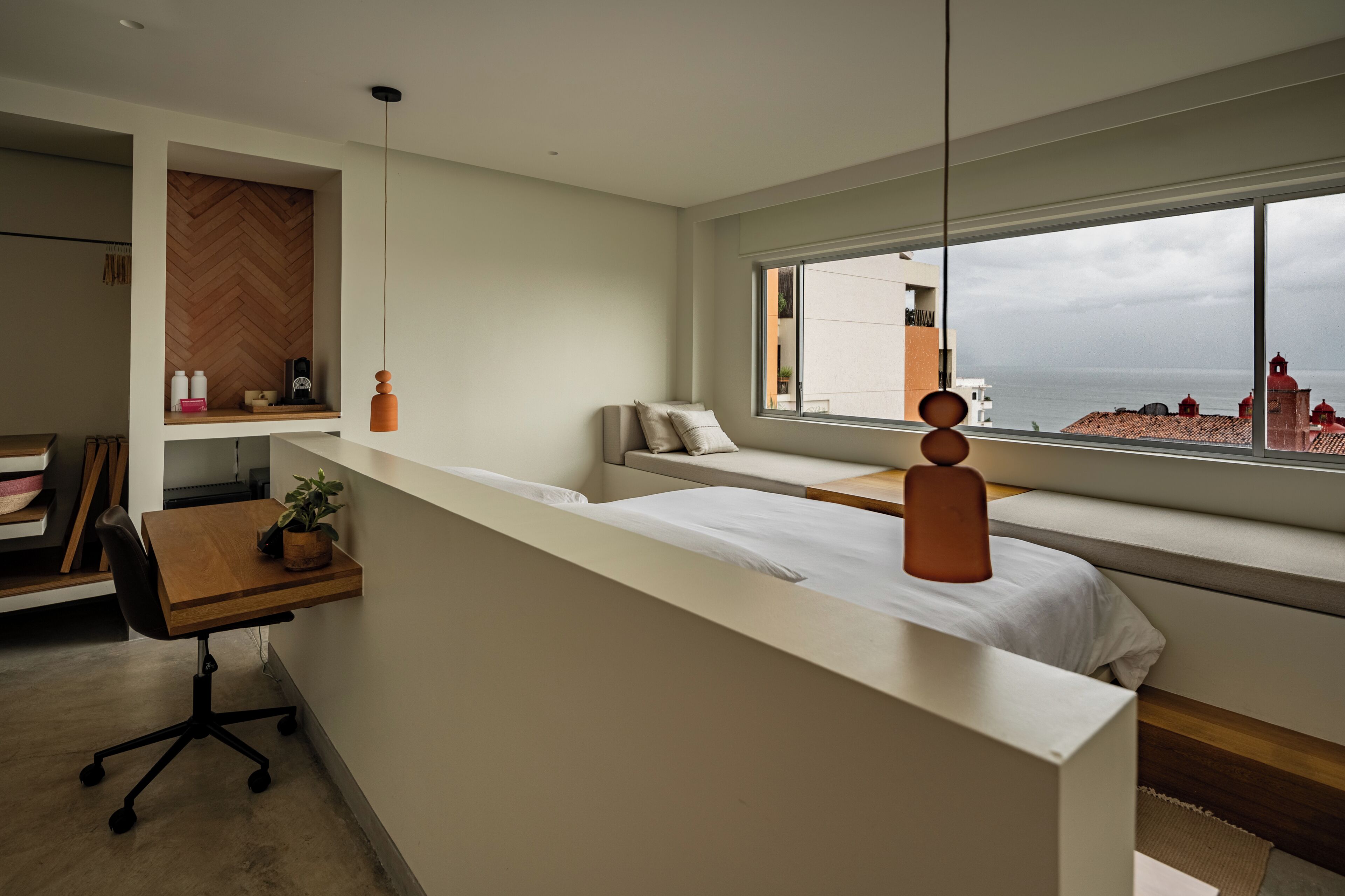 Et moderne hotelværelse med et stort vindue, et skrivebord, en seng og et siddeområde.