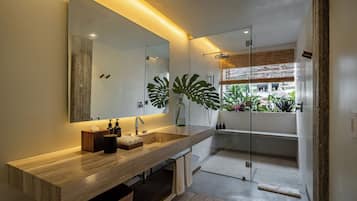 A modern bathroom with a wooden vanity, a large mirror, and a glass shower enclosure.