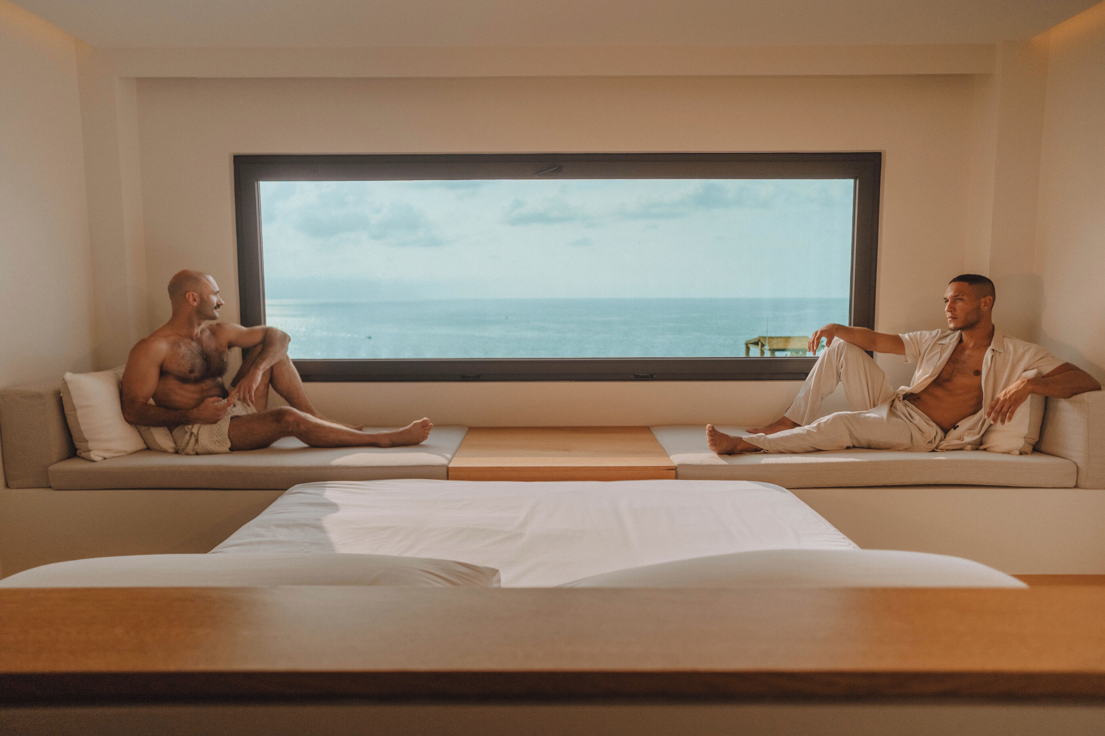 A room with a large window, a sofa, and a bed.