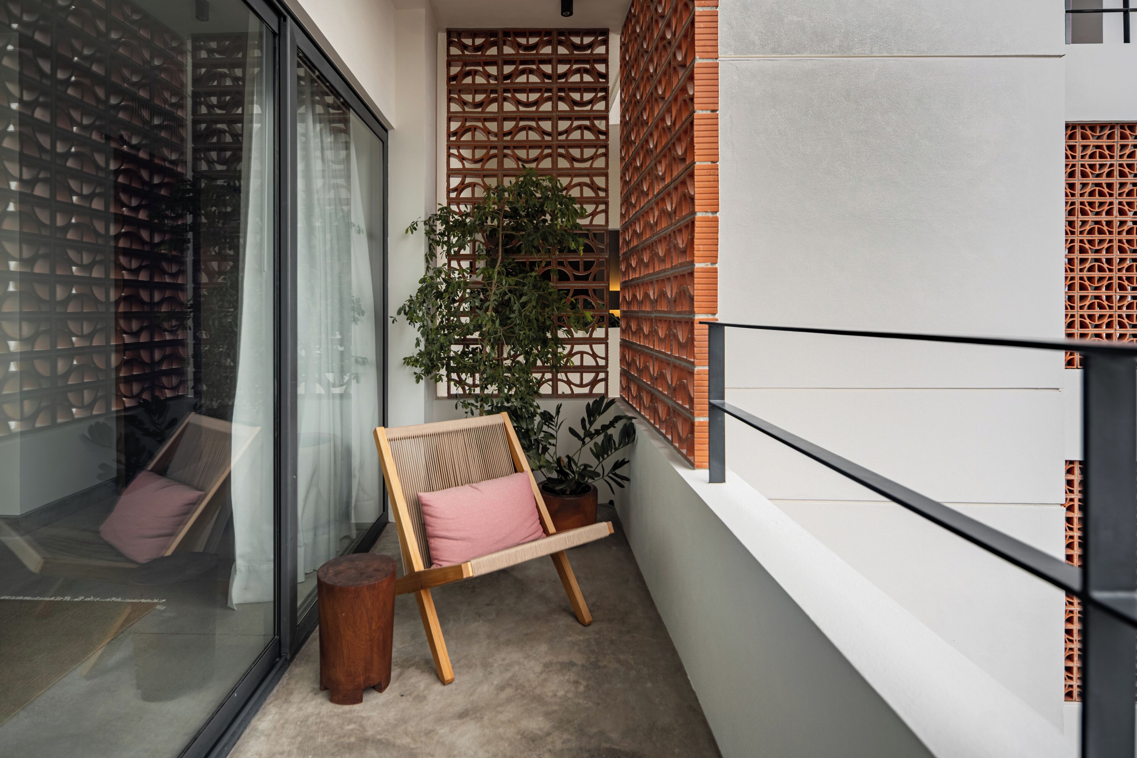 A balcony with a wooden chair, a potted plant, and a decorative wall.