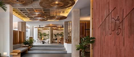 A modern interior with a wooden reception desk, seating area, and a large wooden wall with a logo.