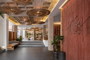 Un interior moderno con mostrador de recepción de madera, zona de estar y un amplio panel de madera con un logotipo.