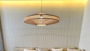 Una sala moderna con un sofá modular, una mesa de centro de madera y una lámpara colgante de fibras.