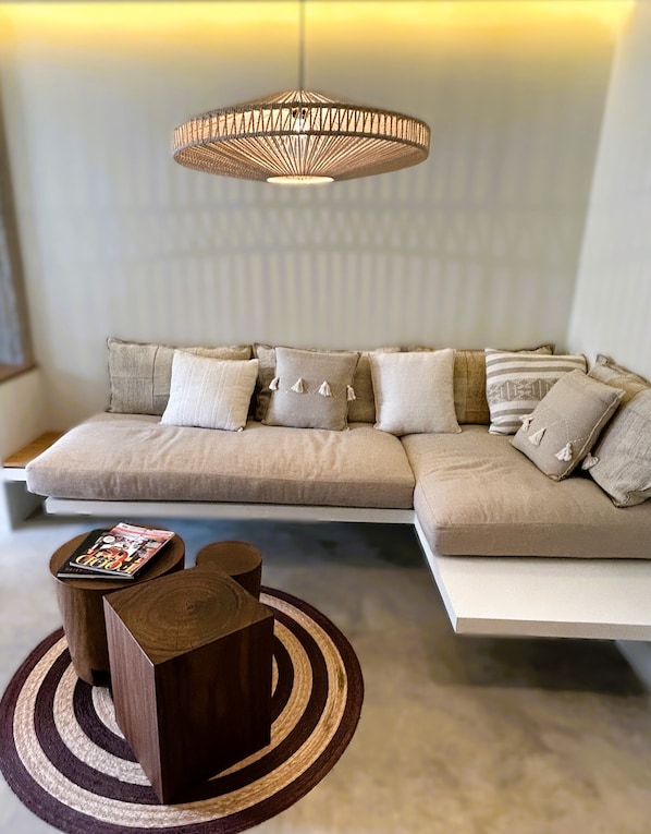 A modern living room with a sectional sofa, a wooden coffee table, and a woven pendant light.