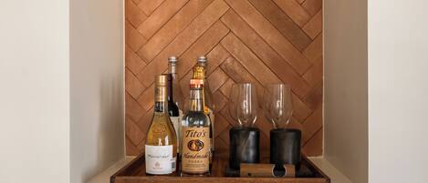 A wooden herringbone wall with a shelf containing bottles and glasses.
