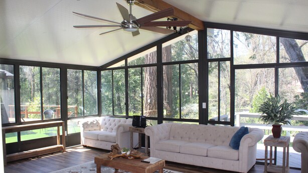 A spacious room with large windows, a ceiling fan, and two white sofas. - Luxury Mountain Home with Fireplace, Yosemite & Bass Lake (Oakhurst)