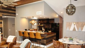 A modern kitchen with a central island, wooden chairs, and a dining table set for six. - Luxury Mountain Home with Fireplace, Yosemite & Bass Lake (Oakhurst)