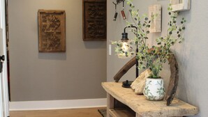 A hallway with a wooden bench, a rustic wall decor, and a hanging light fixture. - Luxury Mountain Home with Fireplace, Yosemite & Bass Lake (Oakhurst)