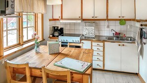 Une cuisine avec une table en bois, des chaises, une cuisinière, un évier et des placards.