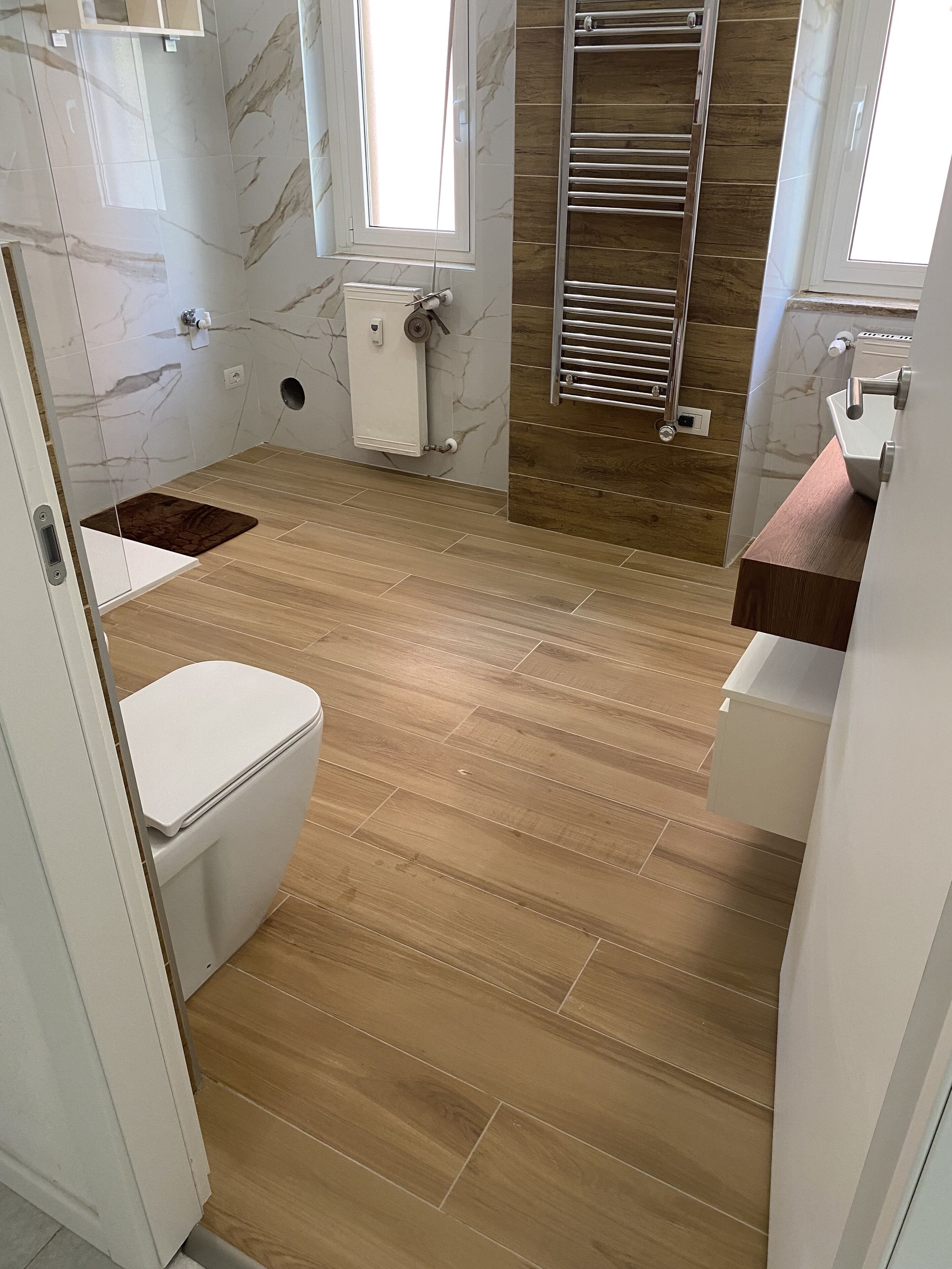 Ein Badezimmer mit Toilette, Waschbecken, Dusche und Holzboden.