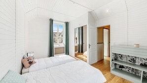 Une chambre avec un grand lit, une coiffeuse avec un miroir et une vue sur l’extérieur.