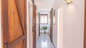 A hallway with wooden doors, a potted plant, and a tiled floor. - Villa Cuqui Antequera by Ruralidays (Málaga)
