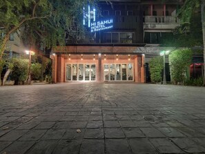 A hostel and restaurant with a large glass entrance, paved walkway, and surrounding greenery. - Hi Samui Hostel (Koh Samui)