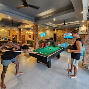 A pool table in a room with brick walls and a ceiling fan.