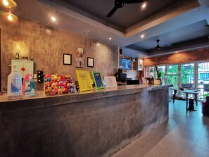 A reception desk with a concrete counter, framed certificates, and a menu board. - Hi Samui Hostel (Koh Samui)