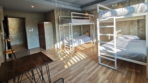 A dormitory room with bunk beds, a wooden table, and a chair. - Hi Samui Hostel (Koh Samui)