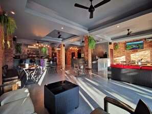 A spacious bar area with a counter, seating, and a television screen.