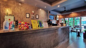A reception desk with a concrete counter, framed certificates, and a menu board. - Hi Samui Hostel (Koh Samui)