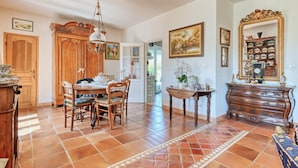 Comedor con mesa y sillas de madera, una araña y piso de baldosas.