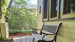 A wooden porch with a bench, a green fence, and a tree. - Ruston House - Port of Echuca (Echuca)