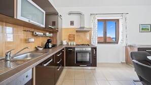 Une cuisine moderne dotée d’un four encastré, d’une plaque de cuisson et d’une grande fenêtre offrant une vue sur la mer.