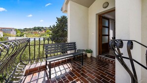 Un balcon avec un banc, un pot de fleurs et une porte donnant sur l’intérieur.