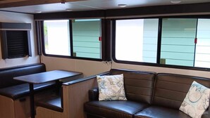 A compact living space with a sofa, a small table, and a bench. - Affordable stay 7 minutes to the beach 2021 32' RV (Navarre)