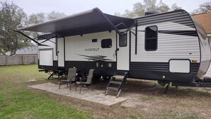 A recreational vehicle with a covered living area, a small kitchen, and a sleeping area. - Affordable stay 7 minutes to the beach 2021 32' RV (Navarre)