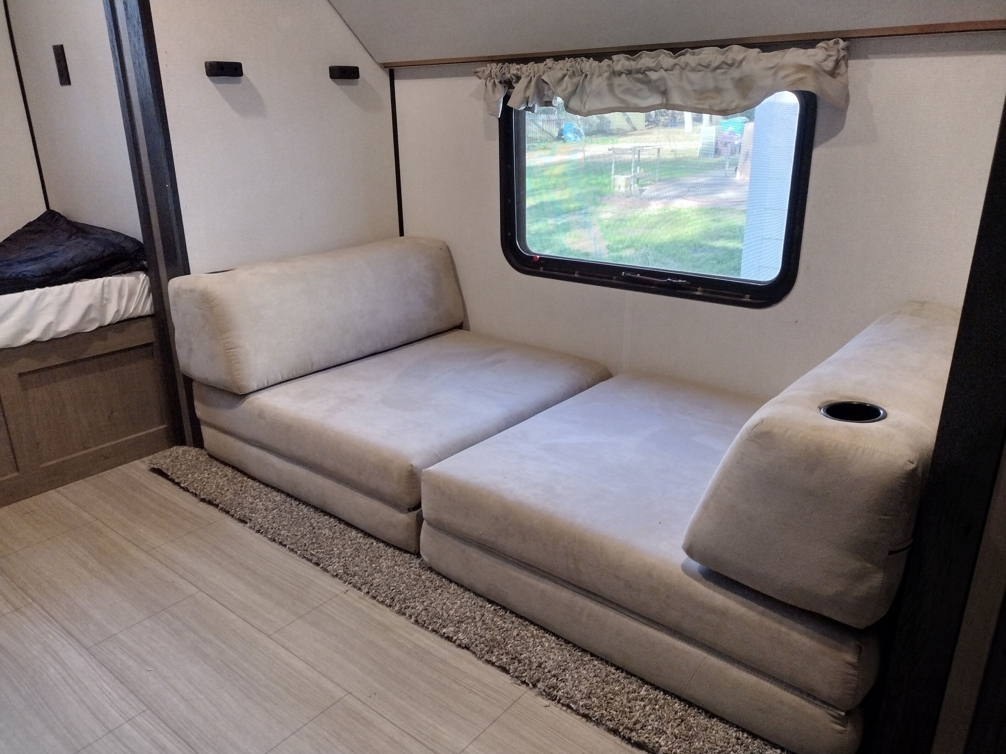 Ein kompaktes Wohnmobil-Interieur mit einer Sitzecke, einem Fenster und einem kleinen Tisch.
