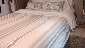 A bedroom with a bed, pillows, and a headboard. - Affordable stay 7 minutes to the beach 2021 32' RV (Navarre)