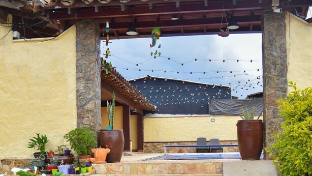 A stone staircase leading to a covered patio area with outdoor seating and potted plants. - Hostal Hollywood Inn II (Rionegro)
