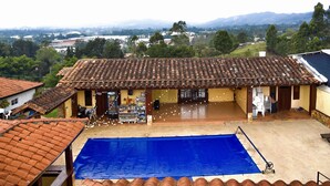 A building with a tiled roof and a blue pool area. - Hostal Hollywood Inn II (Rionegro)